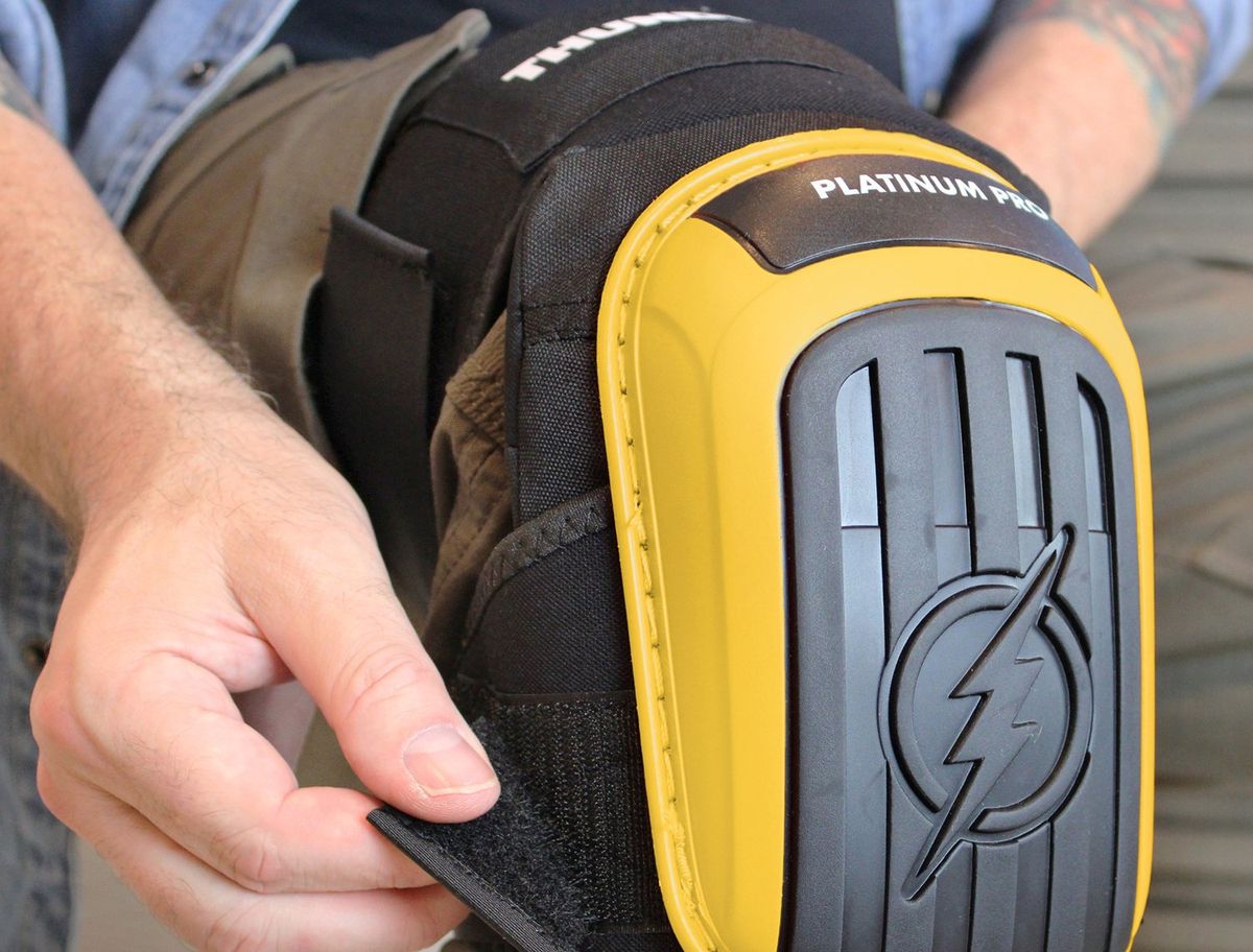 Close-up of hands fastening the strap on a yellow Thunderbolt knee pad